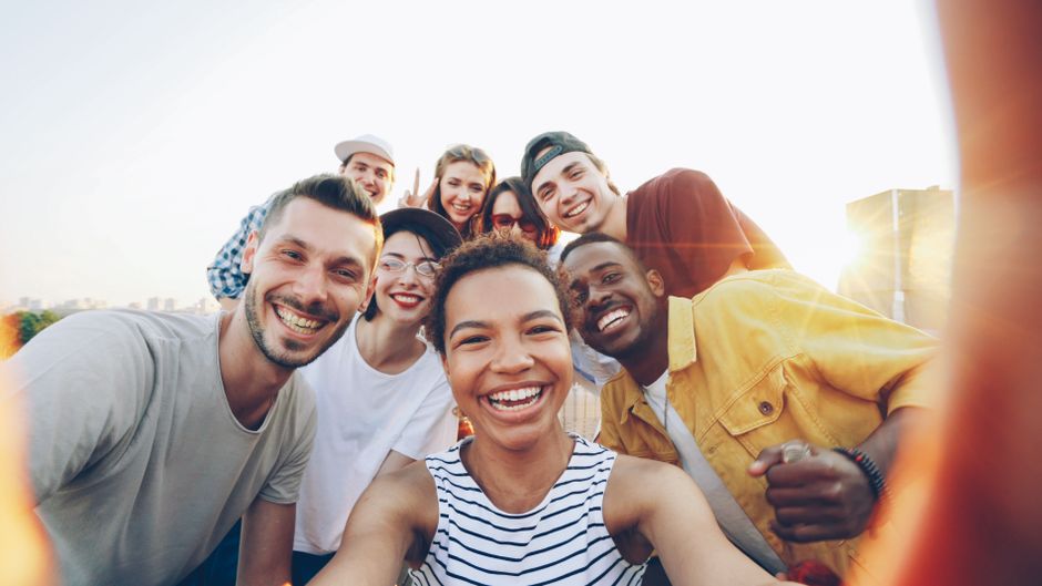 Home A diverse group of friends taking a joyful selfie outdoors during sunset.