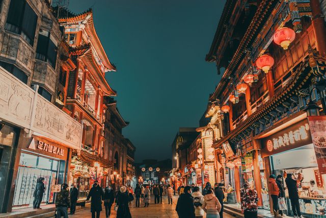 Lively urban scene of a Chinese street at night with traditional architecture and bustling crowd.